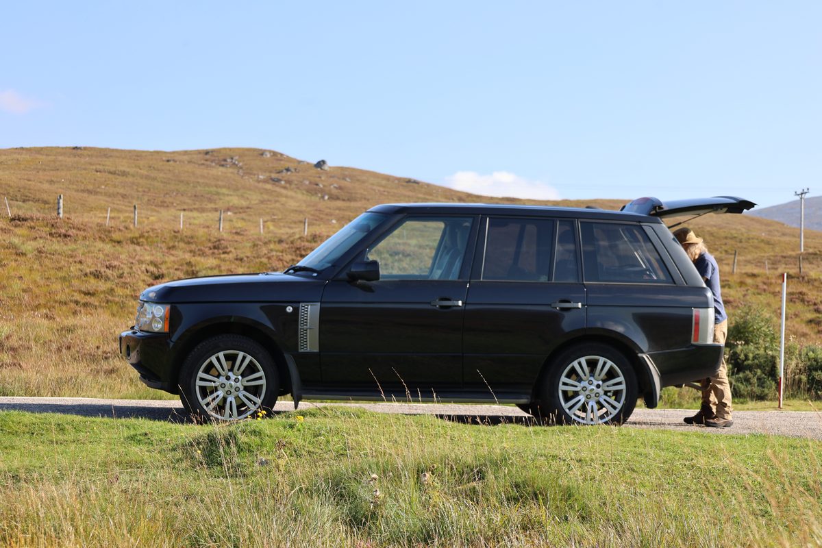 Range Rover L322 in black, side profile, parked in the Scottish Highlands with the tailgate open